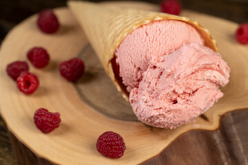 pink sweet raspberry-flavored ice cream lies on a walnut board, ripe red raspberries and raspberry cold natural ice cream on the table, close up