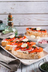 Appetizing bruschetta with ricotta, tomato, radish and quail egg on a plate vertical view