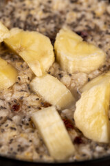 add pieces of ripe banana to quickly cooked oatmeal porridge, boiled oatmeal porridge with chia seeds, berries and fresh banana