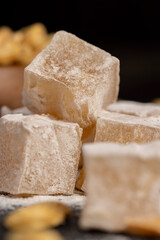 Turkish delight in with nuts , scattered oriental sweets Turkish delight with peanuts on a black board, closeup, side view