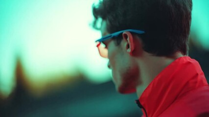 A focused young athlete stands confidently outdoors, radiating energy with vibrant colors and a charming smile. The setting sun casts a warm glow, highlighting his spirited vibe