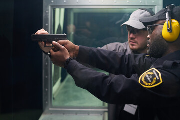 Instructor teaching safety measures at indoor shooting range, ensuring proper handling of firearm...