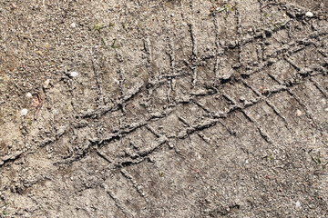 Tire track on dry ground. Close-up of off-road vehicle mark. Rough dirt with pattern imprint. Outdoor adventure trace. Heavy wheel trail in soil. Grunge natural texture. Rural terrain background.