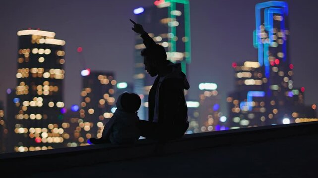 Father and son sitting on a rooftop are enjoying the magical view of the illuminated dallas skyline at night, creating a heartwarming moment of connection and shared wonder