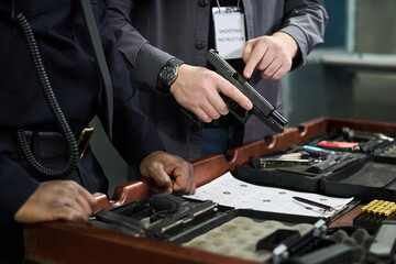 Shooting instructor explaining usage of firearms and safety procedures, demonstrating techniques with various setup on a desk, focusing on hand positions and equipment handling