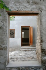 The stunning architectural elegance of a contemporary interior is beautifully revealed through an open doorway set within a rustic stone wall, illuminated by daylight