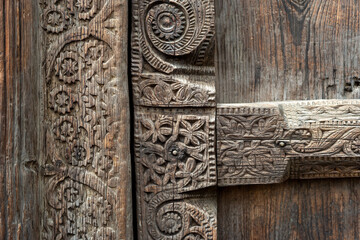 Close-up of intricate floral wood carvings on an antique door, showcasing traditional craftsmanship and aged wooden texture.