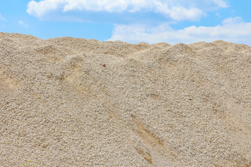 Close-up textural detail of beige sand aggregate pile showing granular construction material surface patterns