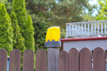 Yellow container or storage unit positioned behind wooden fence in residential backyard setting