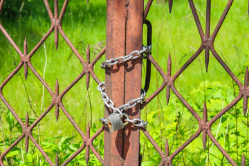Chain-link fence with diamond pattern wire mesh and green vegetation background in close-up detail