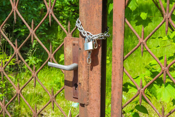 Wooden fence post with chain-link attachment and metal hardware against green foliage background
