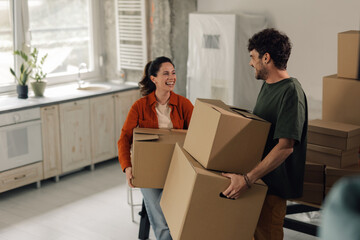 Happy couple carrying cardboard boxes is moving into new home