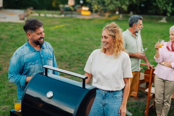Friends enjoying barbecue party in backyard, grilling food and having fun