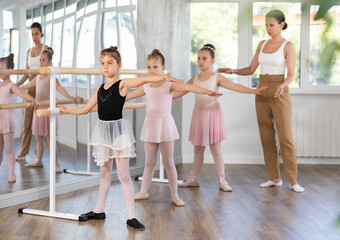 Little girls at the barre learning to get into the second position of ballet choreography © JackF