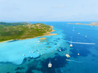 Island in the middle of the sea. Drone view of a yachts, boats and island. Vacationing people. North-eastern Sardinia, Maddalena Archipelago. Vacation and holidays. Summer time for sea travel.