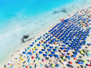 Summer vacation and rest. Beach, people and umbrellas. Top view from drone at the beach and azure sea. View on the coast from drone. Background, wallpaper, postcards.