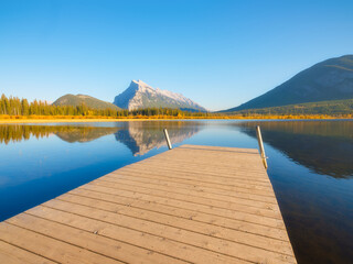 Vermilion lakes. Banff National Park, Alberta, Canada. Reflections on the surface of the water. Pier in the water. Mountains and forest. Background, wallpaper, postcards.