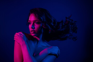 Sensual young woman in neon lighting poses with grace, showcasing beauty, fashion, and glamour