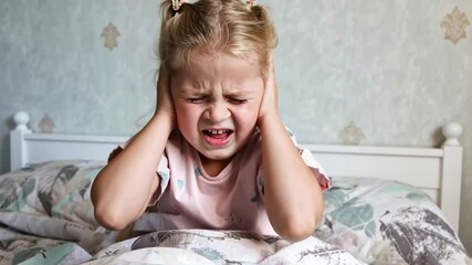 Little child closing ears with hands. The fear of loud sounds, ache or noise
