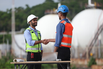 Fototapeta premium An engineer shakes hands with a project manager outside an industrial factory, symbolizing cooperation on an engineering project