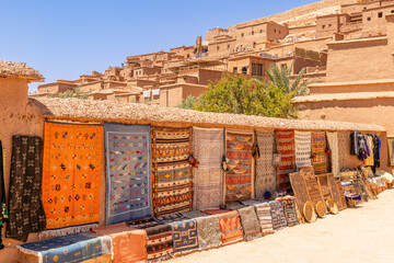Colorful traditional carpets and other gifts selling on the market streets of ancient Ait Benhaddou ksar village, Ouarzazate province, Morocco
