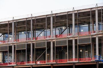 A multi-level data center under construction shows exposed steel framing, temporary safety netting,...
