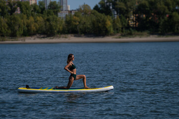 Caucasian woman doing yoga on a SUP board. 