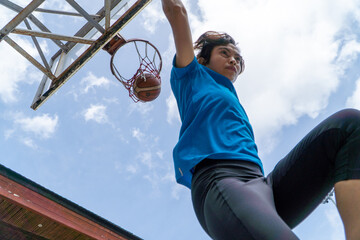 Denpasar, 13 Feb 23: A young athlete performs a slam dunk at a street basketball court under the...
