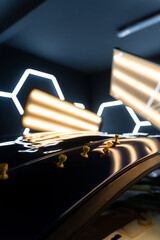 Obraz premium Glue tabs help align and restore the surface for a flawless finish. Multiple glue tabs applied to a dented car roof under LED lights during the paintless dent repair process.