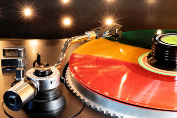 Rainbow-colored vinyl record spinning on turntable. A close-up of the tone arm.