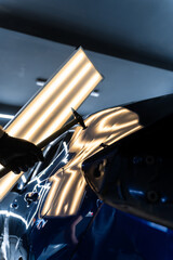 Paintless dent repair PDR involves tapping dents under light reflection for precision. Technician...
