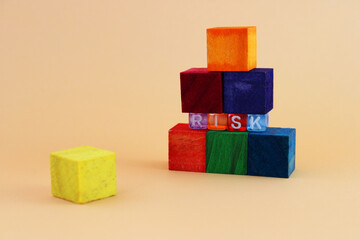 Levels built with colorful wooden blocks are supported by smaller ones that form the word RISK