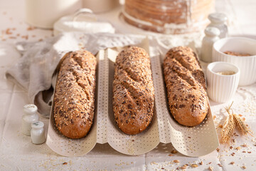 Tasty and homemade wholegrain baguettes baked on baking tray.