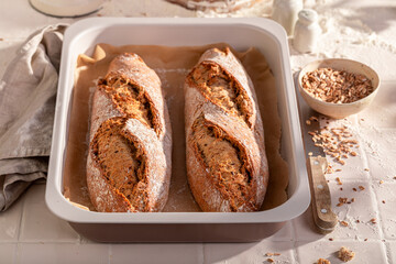 Homemade and tasty baguettes baking in with ears and grain.