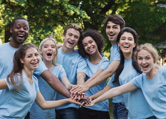 Group of international young people building team outdoor in park, join hands together, copy space