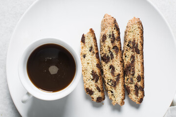Overhead view of chocolate chip biscotti and coffee on white plate, top view of chocolate chip cantucci cookies on a white backgound