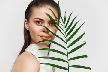 Fototapeta premium Portrait of a young woman with a tropical leaf, showcasing natural beauty and elegance, perfect for lifestyle and wellness themes.