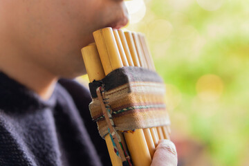 Man playing traditional Andean pan flute outdoors

