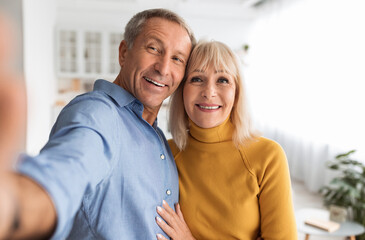 Happy Senior Couple Making Selfie Hugging Posing Together Smiling To Camera Standing At Home....
