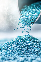 Small blue plastic pellets are pouring from a container, forming a pile. Material, production process, industry