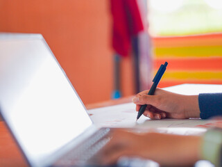 Business woman analyzing chart economic, financial. Closeup hand pen employee with paper work. Technology concept remote work, startup or small business. People using phone, laptop meeting online 