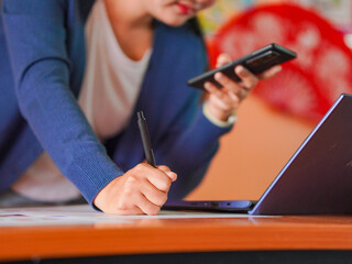 Business woman analyzing chart economic, financial. Closeup hand pen employee with paper work. Technology concept remote work, startup or small business. People using phone, laptop meeting online 