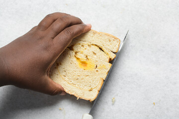 Overhead view of bread being sliced into cubes on a white countertop, process of making bread pudding