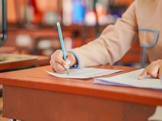 Closeup of female student's hand doing exam in classroom. School proficiency test. Asian student doing exam. Education, learning