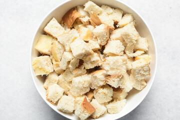 Overhead view of bread cubes in a white bowl, process of making bread pudding