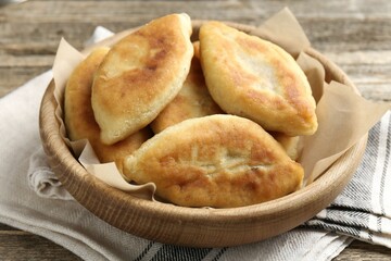 Delicious fried pyrizhky (stuffed pies) on wooden table, closeup