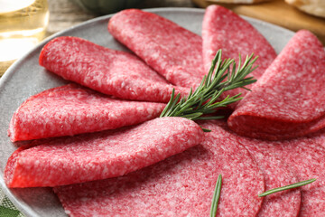 Slices of delicious sausage with rosemary served on table, closeup