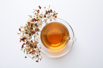 Delicious herbal tea and dry leaves on white background, top view