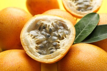 Ripe passion fruits and leaves on yellow background, closeup