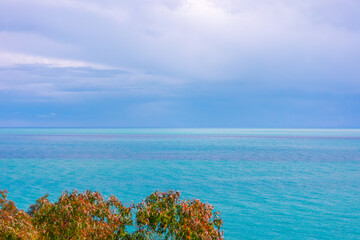 Breathtaking ocean scene with clear turquoise waters stretching to horizon beneath cloudy sky. In...